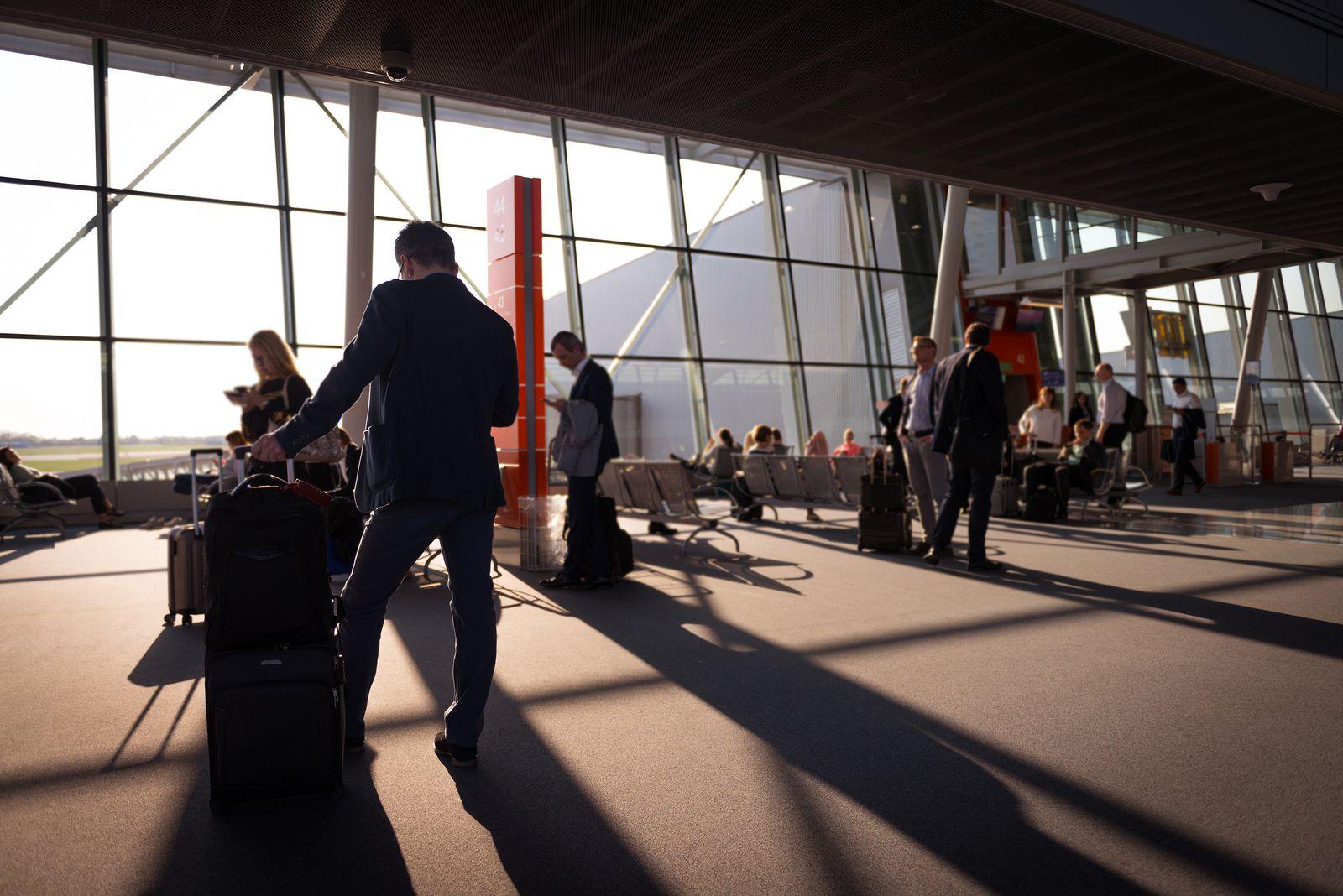 Travellers with carry-on luggage waiting in a busy airport terminal