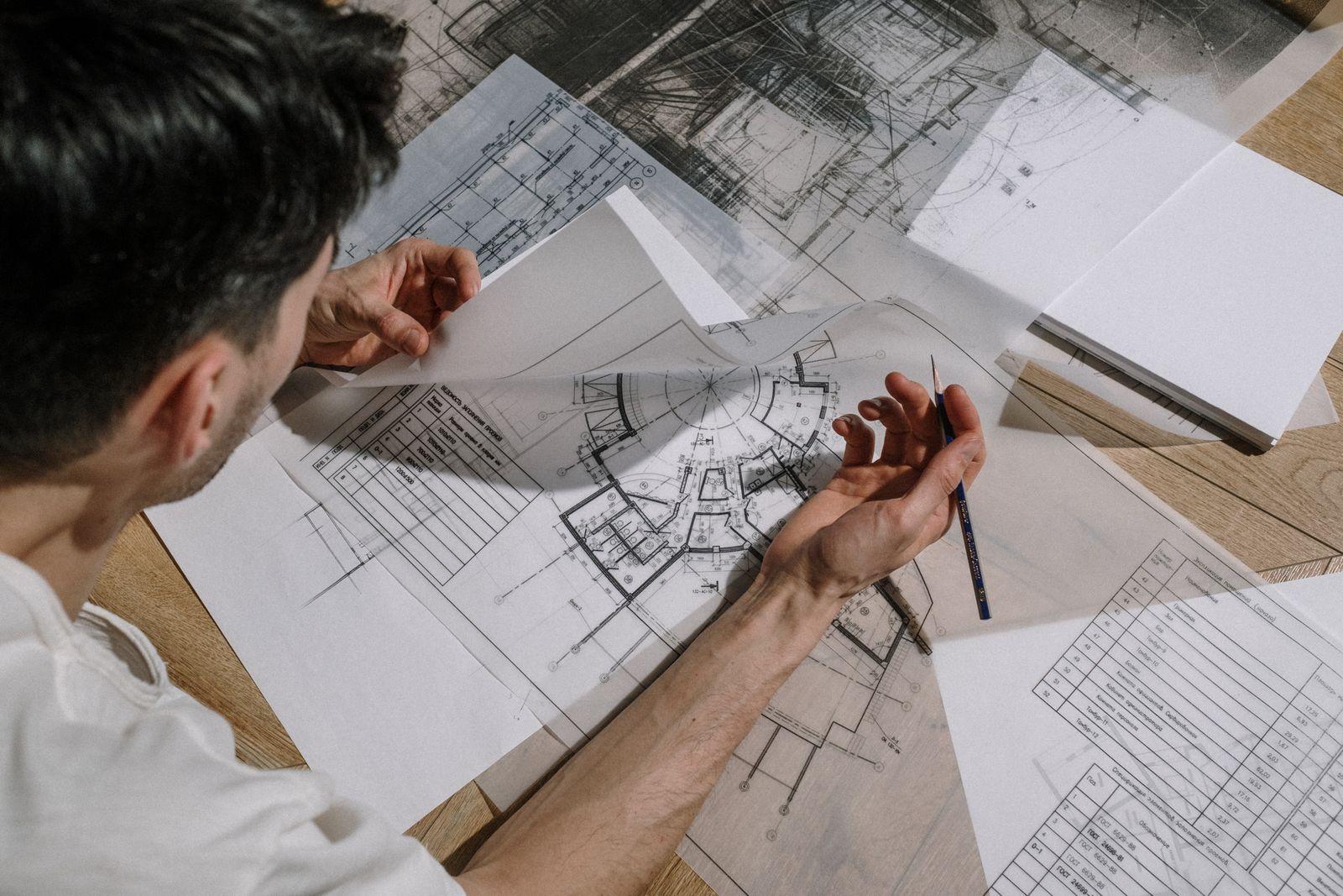 Engineer sketching over technical blueprints at a drafting table