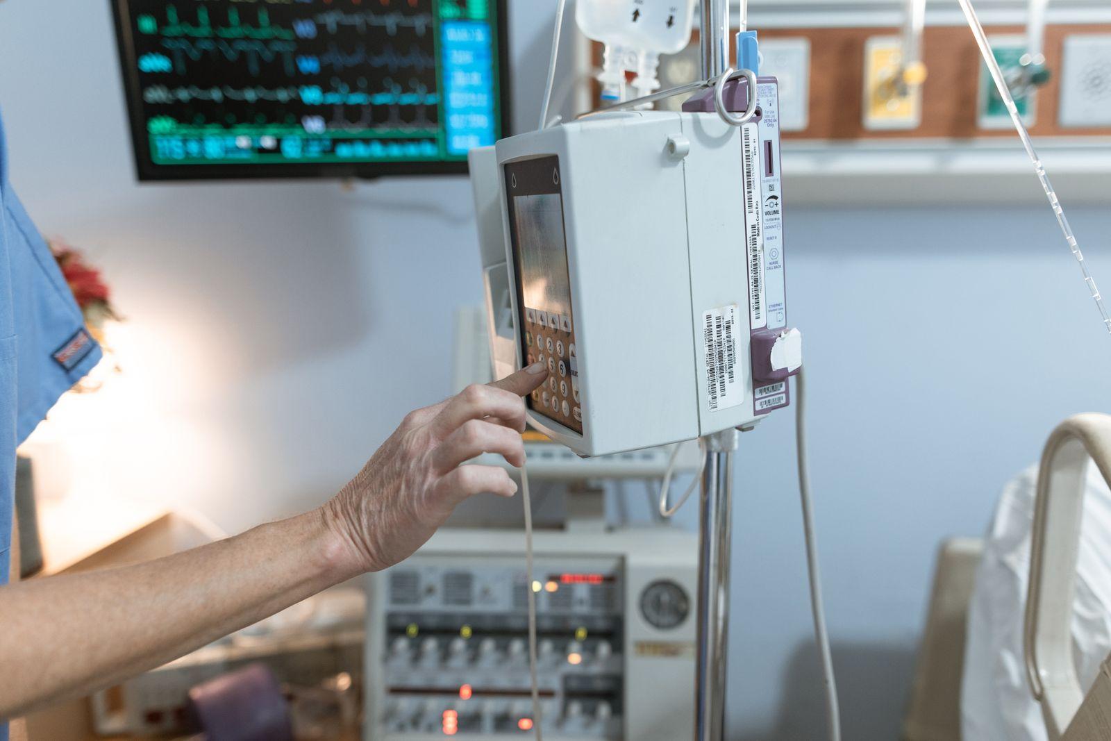 Healthcare worker operating an infusion pump at a patient's bedside