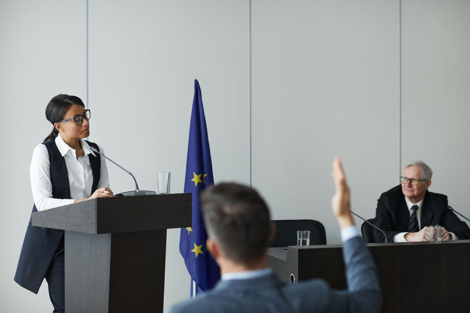 Delegates listening as a speaker addresses a multilingual conference from a rostrum