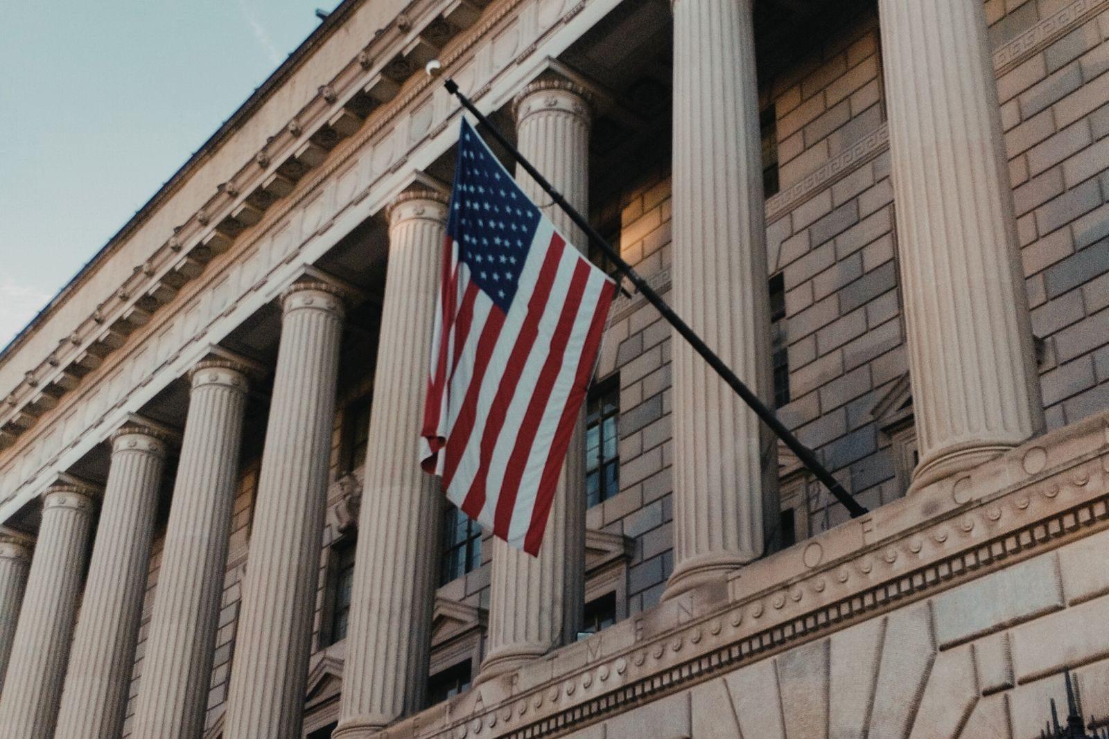 United States flag hanging on the columned facade of a federal government building